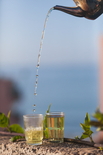 Moroccan green mint tea being poured into a glass.