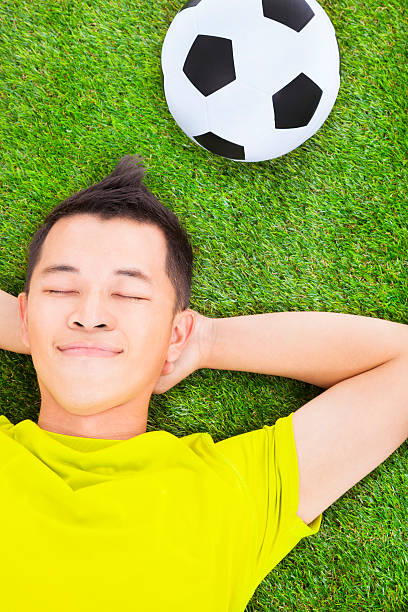 istock young man lying on a meadow with a football 491066851