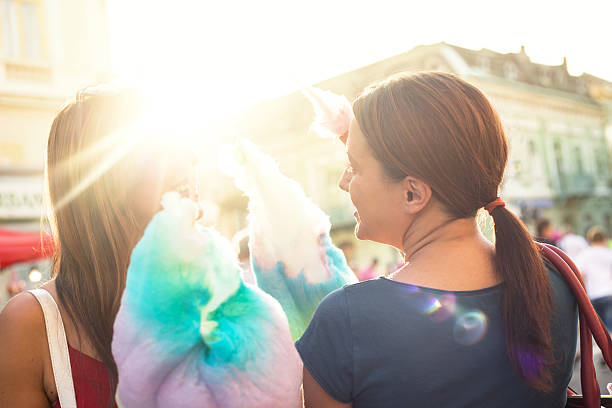 young women eating cotton candy and enjoying stock photo