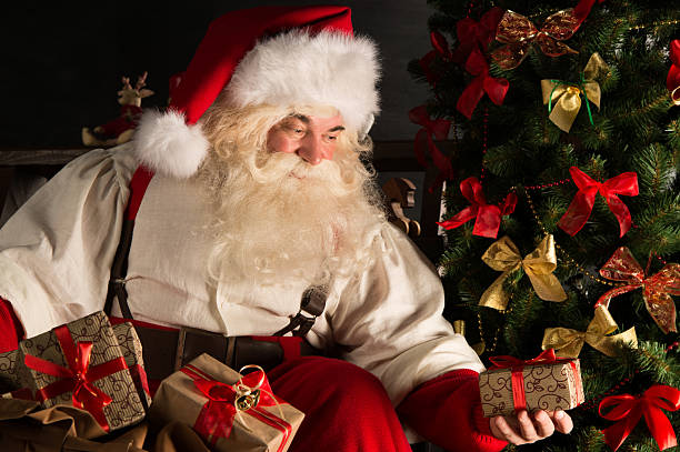 istock Santa putting gifts under Christmas tree in dark room 491069246