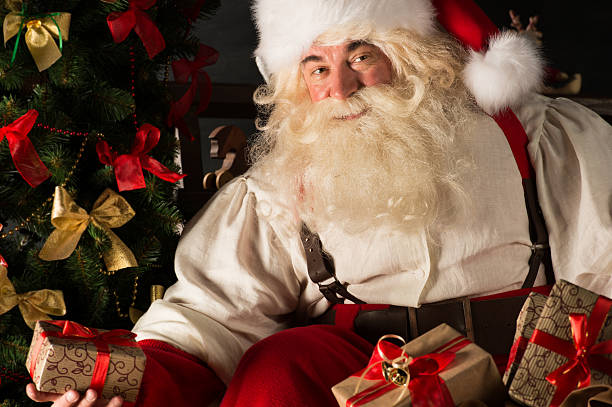 istock Santa putting gifts under Christmas tree in dark room 491069388