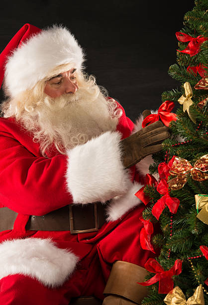 istock Santa Claus decorating Christmas tree in dark room 491071046