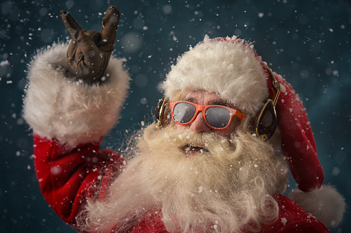 Santa Claus is listening to music in headphones wearing sunglasses. Christmas.