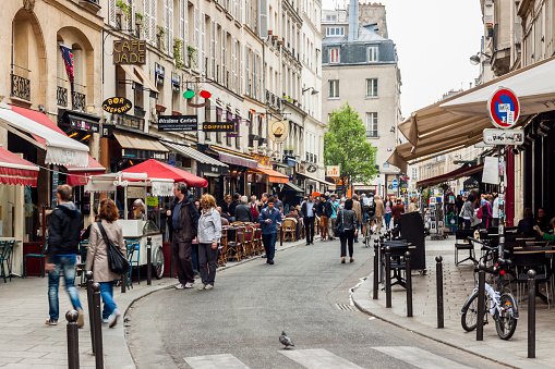 Paris, France - April 26, 2013: Tourists walk past a cafeteria and souvenir store. Paris is the most visited city in the world.