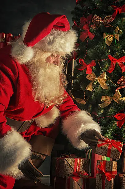 Photo of Santa is placing gift boxes under Christmas tree