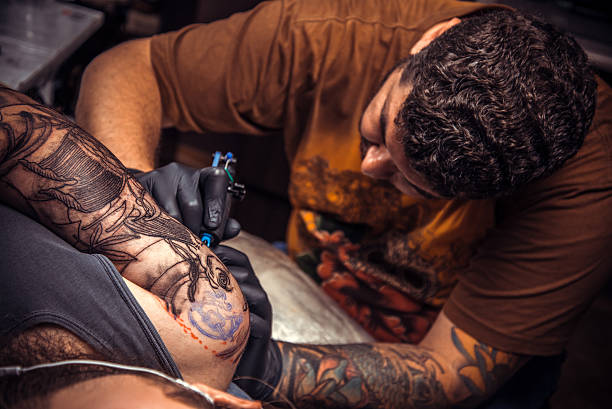Man wearing gloves making a tattoo in tattoo parlor