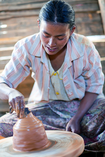Nyaung Shwe, Myanmar - January 12, 2012: Young Burmese craftswoman working in a ceramics manufacture.