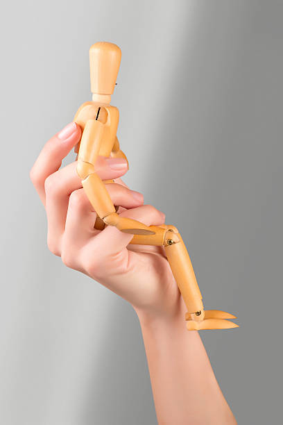 female hand holding a wooden mannequin seated