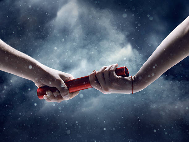 Close up of exchanging relay baton on a race Close up of exchanging relay baton on a race on a black background with smoke and snow relay stock pictures, royalty-free photos & images