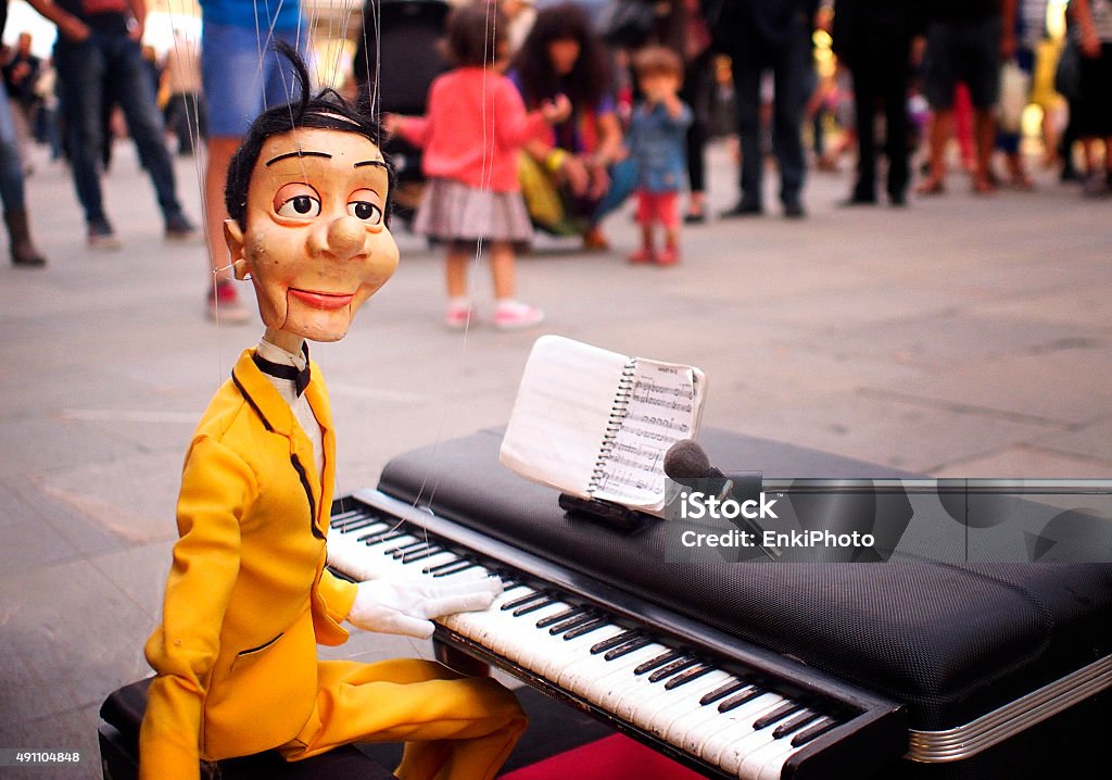 Male marionette in a street show Street show. Male marionette in action as a pianist. Outdoors Stock Photo