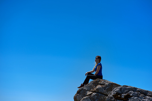 side view of hiker woman on top of mountain looking at view and enjoying such an amazing day.