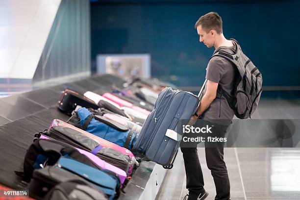 Young Man Collecting His Luggage Stock Photo - Download Image Now - Airport, Luggage, Checked Pattern