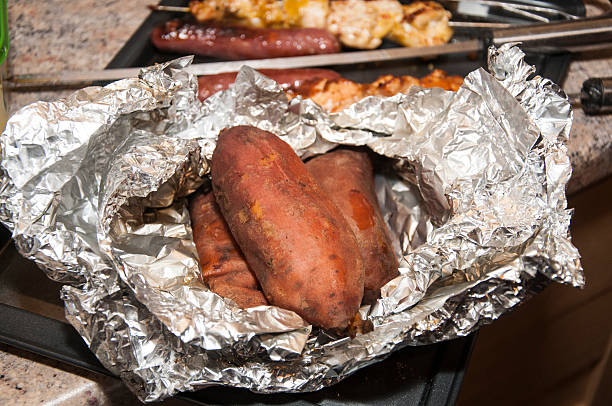 Close-up image of a aluminum ￼foiled covered baked potato in a oven in a residential home kitchen