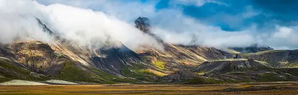 Photo of Clouds rolling over dramatic mountain panorama to valley below Iceland
