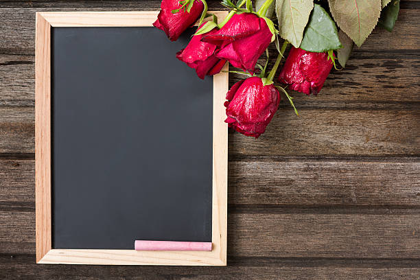 istock Black board and red roses on wooden background, top view 491131802