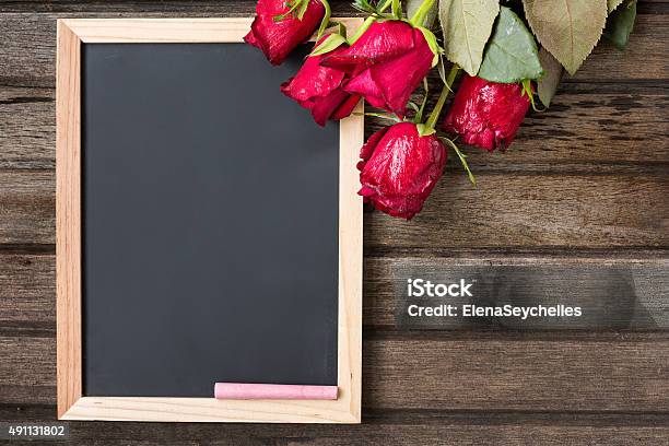 Black Board And Red Roses On Wooden Background Top View Stock Photo - Download Image Now