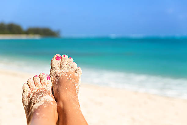 Holiday concept. Woman feet close-up relaxing on beach, enjoying stock photo