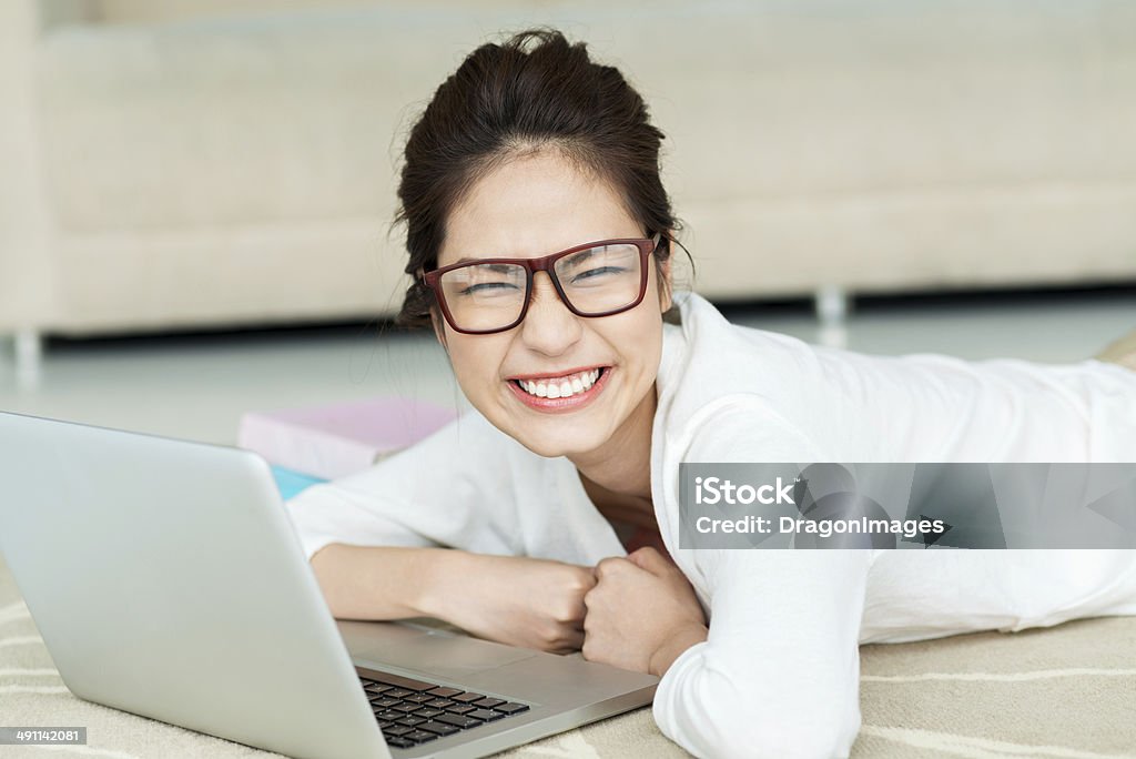 On the floor Young woman lying on the floor and working on her notebook Adult Stock Photo