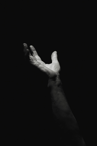 Hand emerging from the dark. Help wanted. Black and white