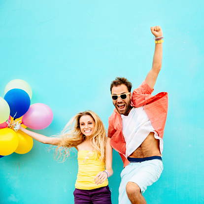 Happy couple with balloons jumping