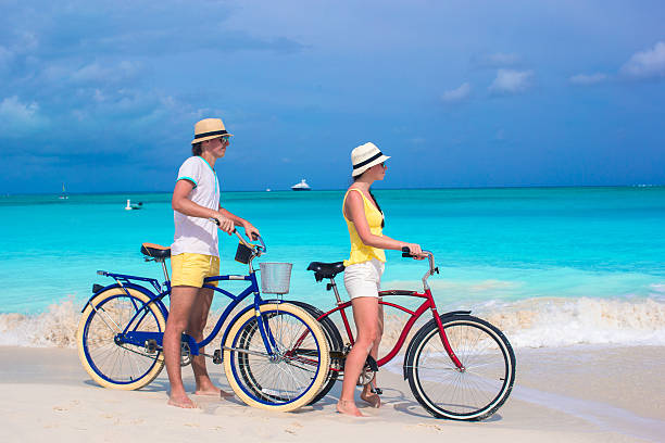 istock Young happy couple riding bikes on white tropical beach 491144539