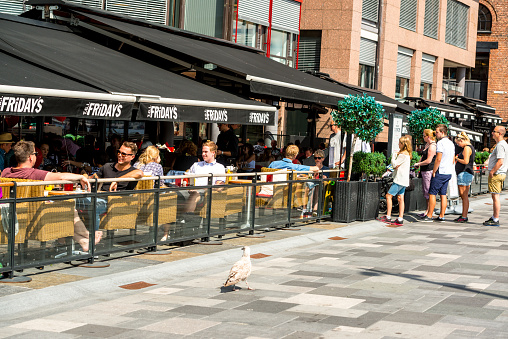 Oslo, Norway - July 23, 2015: People enjoying lunch outdoors in T.G.I. Friday's, Oslo. Few people are waiting in line at the entrance to be seated. 
