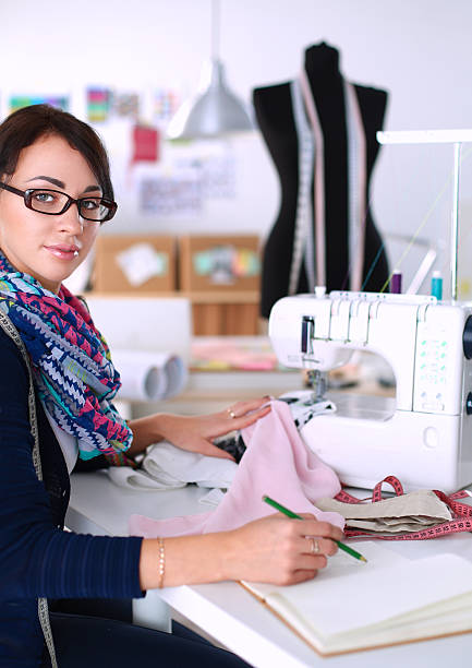 istock Young woman sewing while sitting at her working place 491152072