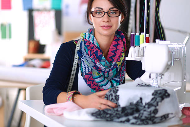 istock Young woman sewing while sitting at her working place 491152152