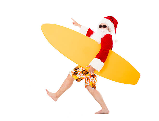 Happy Santa Claus holding surf board with pointing gesture