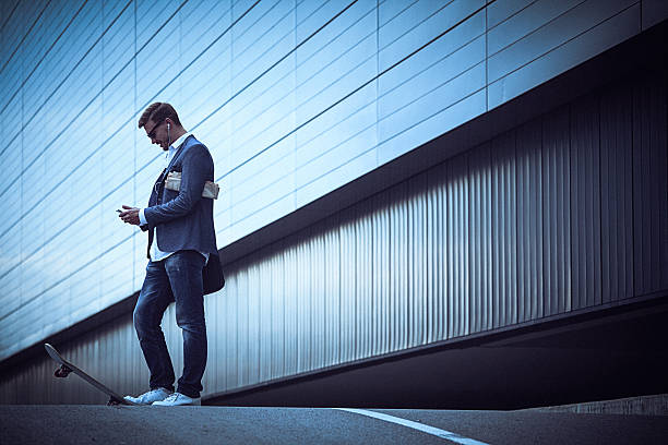 istock Young businessman with skateboard using smartphone in the urban 491168164