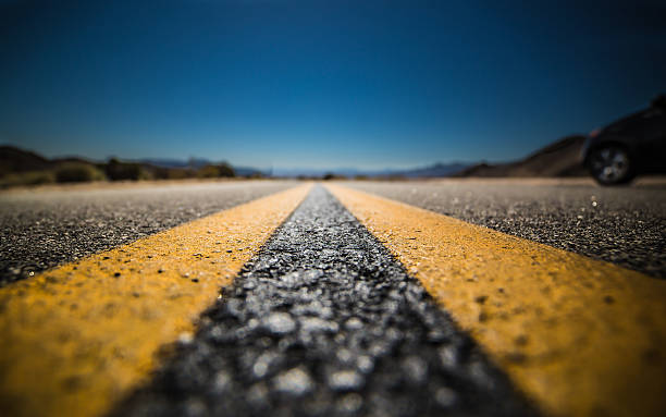 Middle of the Road Photo was taken at Joshua Tree National Park.  A narrow depth of field was used to take this photo at the ground level to emphasize and focus on one key area of the road; a metaphor for staying in the present, the blurred past and the unknown future and possibilities ahead.   middle of the road stock pictures, royalty-free photos & images