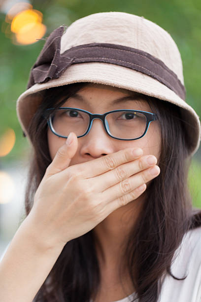 istock asia woman hand shield mouth 491172472
