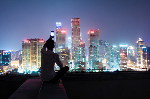 Young man using smart phone take photo in city night