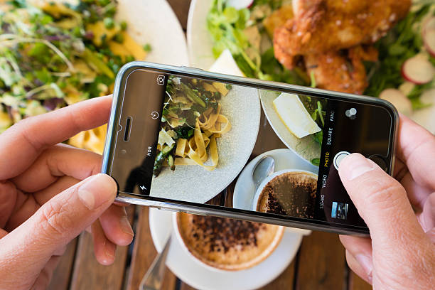 Melbourne, Australia - Oct 1, 2015: Top down view of a woman taking photo of a meal using the camera app in an iPhone