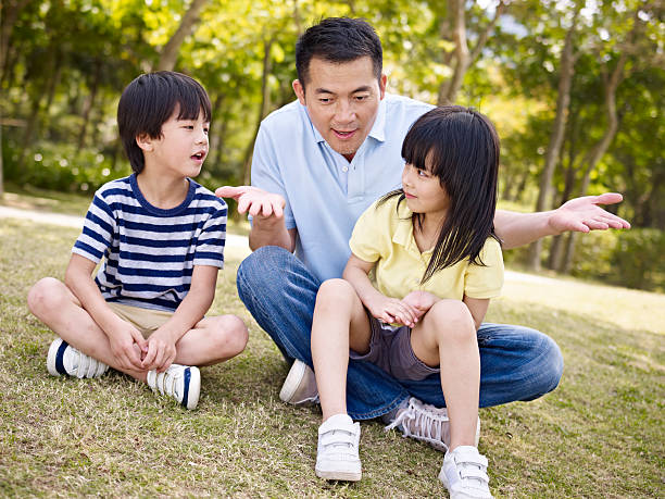 istock asian father and children talking in park 491185816