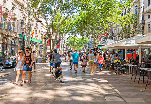 La Rambla in Barcelona, Spain Barcelona, Spain - July 6, 2015: Hundreds of people promenading in the busiest street of Barcelona, the Ramblas. The street extends 1.2 kilometers connects the Placa de Catalunya in the centre with the Christopher Columbus Monument at Port Vell. la rambla stock pictures, royalty-free photos & images