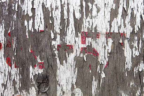 Old wooden surface with the remains of cracked white and red oil-paint