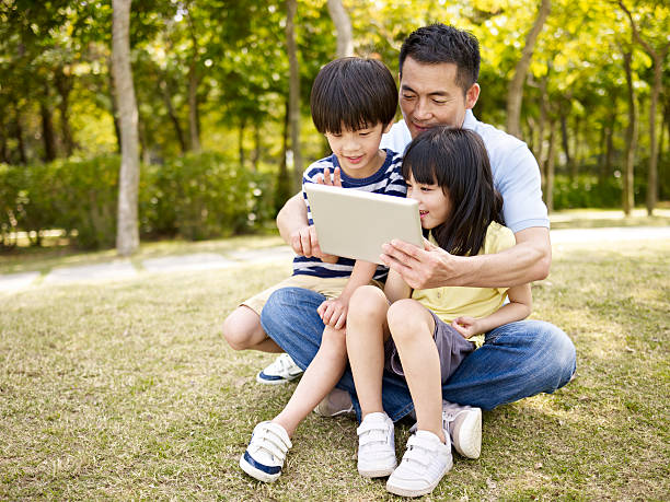 istock asian father and children using tablet outdoors 491200618