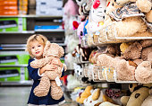 Pretty smiling little girl with teddy-bear in grocery store