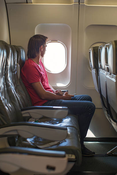 istock Young man looking in window on board of airplane 491204949