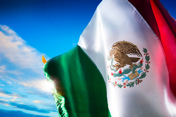A massive Mexican flag flutters against the sky on a bright day