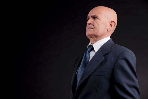 old bald self-confident businessman on a dark background