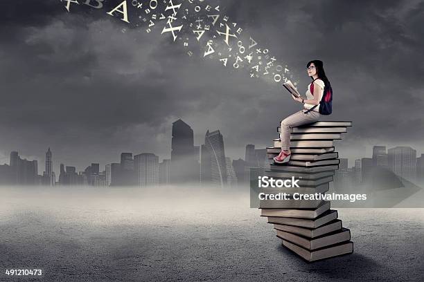 Student Sitting On A Stack Of Books 1 Stock Photo - Download Image Now - Dark, Futuristic, Studying