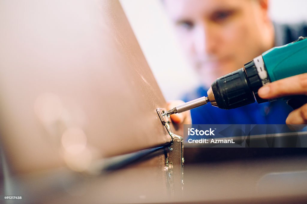 Assembling Cabinet Close-up of carpenter assembling furniture. He is screwing a screw with an electric drill. Selective focus. Furniture Stock Photo