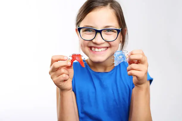 Pretty girl with colored orthodontic appliance .