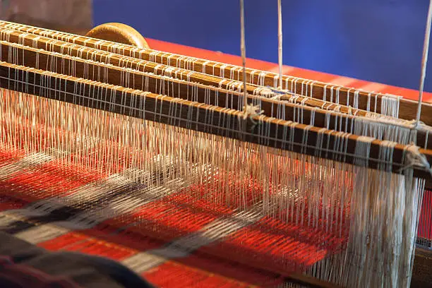 red and white colored weave on a loom