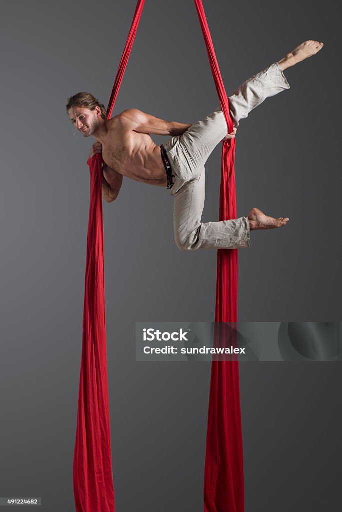 Man performing aerial silk dance Sporty young man doing exercise with elastics, aerial silk ribbons, aerial. Sport training gym and lifestyle concept. Anti-gravity yoga. 2015 Stock Photo