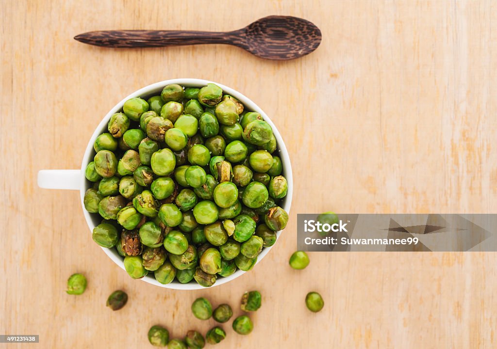 Peas spilling out of a white bowl, Top view Peas spilling out of a white bowl on wooden background, Top view 2015 Stock Photo