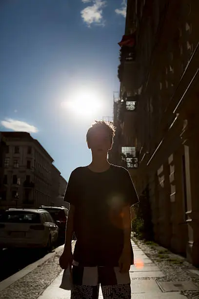 backlit shot of a boy on a street with the sun behind his head