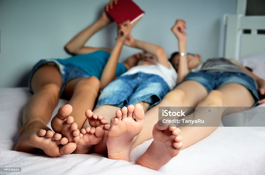 Los niños son yacer en la cama y juegue en el comprimido - Foto de stock de Cama libre de derechos